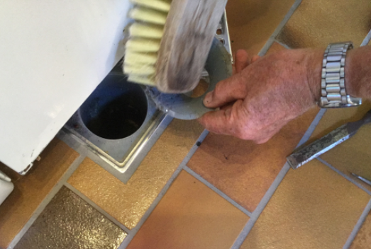 Billede af mand, der vasker afløb rent med en børste.