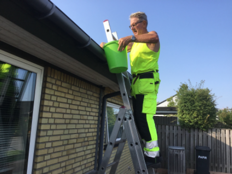Billede af mand, der renser sin tagrende.