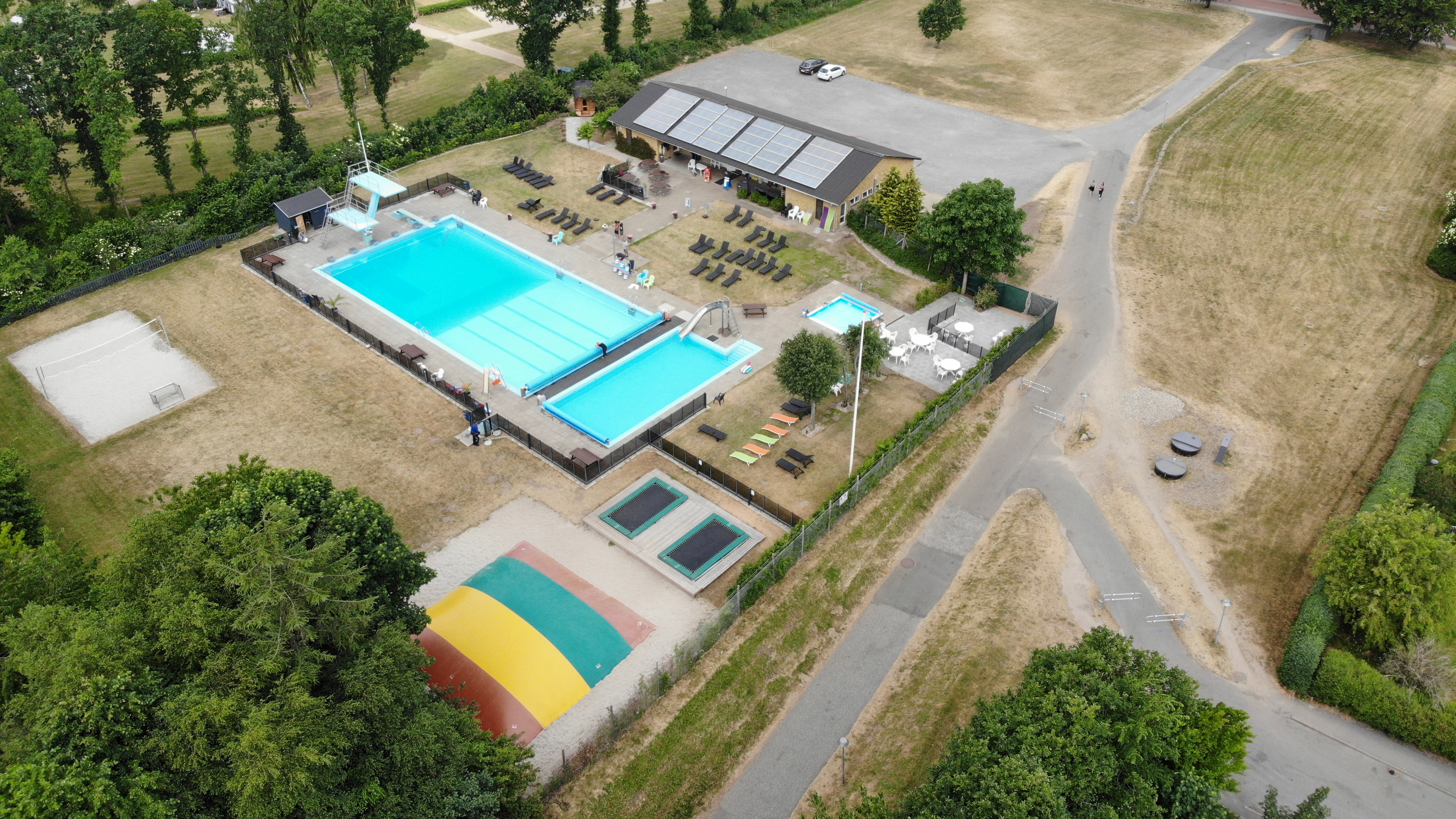 Jelling Friluftsbad luftfoto med bassiner, trampoliner, hoppepude og volleybane
