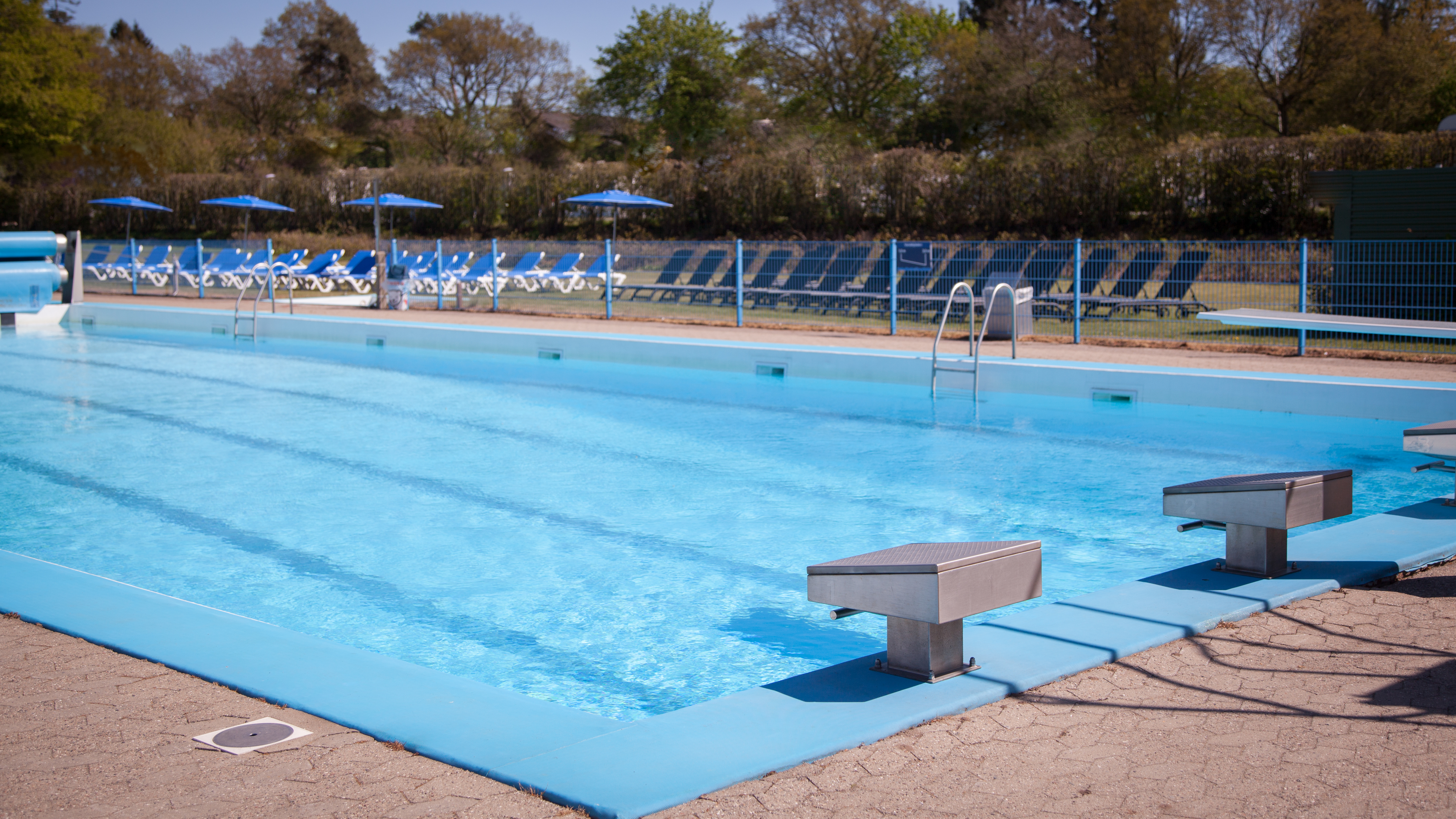 Det storebassin i Give Friluftsbad med startskamler for enden af bassinet og liggestole bag ved på afslapningsområdet